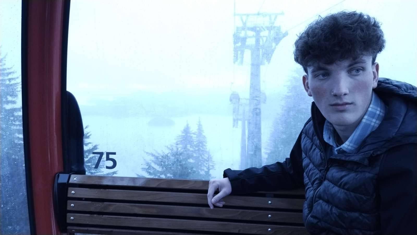 Man sitting on ski lift with snow in the background